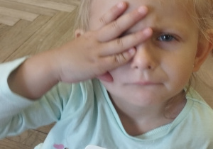 Dziewczynka naśladuje daną emocję z obrazka.