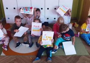 Wspólne zdjęcie grupy z pracami plastycznymi.
