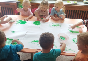 Dzieci malują palcami farbą.