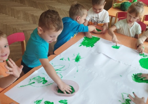 Dzieci malują palcami farbą.