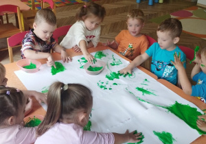 Dzieci malują palcami farbą.