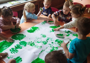 Dzieci malują palcami farbą.