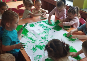 Dzieci malują palcami farbą.