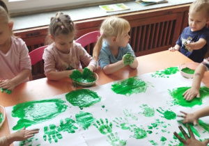 Dzieci malują palcami farbą.