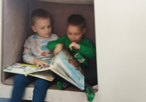 Dzieci oglądają w domku książki.