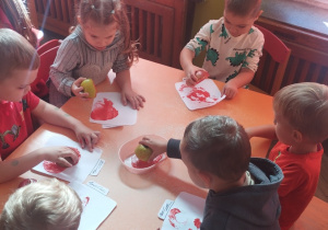 Dzieci stemplują jabłkiem.