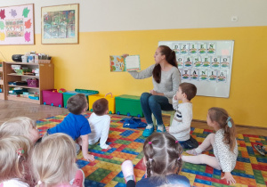 Dzieci słuchają książki czytanej przez panią bibliotekarkę