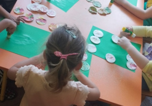 Dzieci przyklejają kolorowe płatki kosmetyczne.