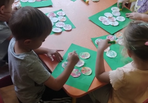 Dzieci przyklejają kolorowe płatki kosmetyczne.