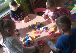 Dzieci układają klocki przy stoliku.