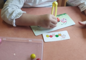 Dziewczynka układa kulki według wzoru.