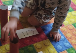 Chłopiec wkłada kasztan do dziupli.