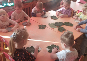 Dzieci odciskają liście na glinie.