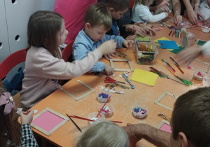 Dzieci wraz z rodzicami tworzą ozdoby podczas zajęć kreatywnych