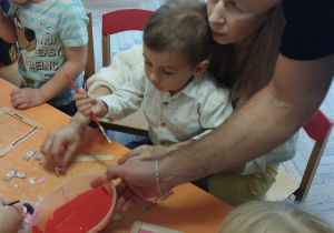Dzieci wraz z rodzicami tworzą ozdoby podczas zajęć kreatywnych