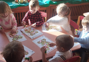 Dzieci przyklejają plastry na rany misia.