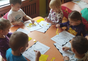 Grupa dzieci wykleja herb Łodzi.