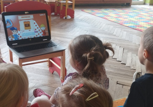 Grupa dzieci ogląda urządzenia domowe na laptopie.