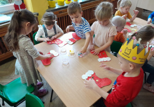 Dzieci przyklejają ozdoby na świąteczną skarpetę