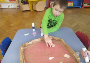 Chłopiec przykleja składniki