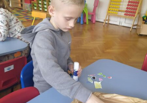 Chłopiec przykleja składniki